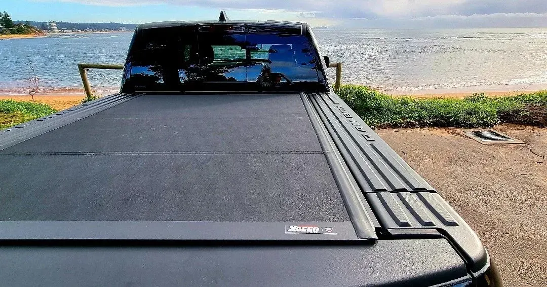 Black pickup truck bed cover with a body of water in the background.