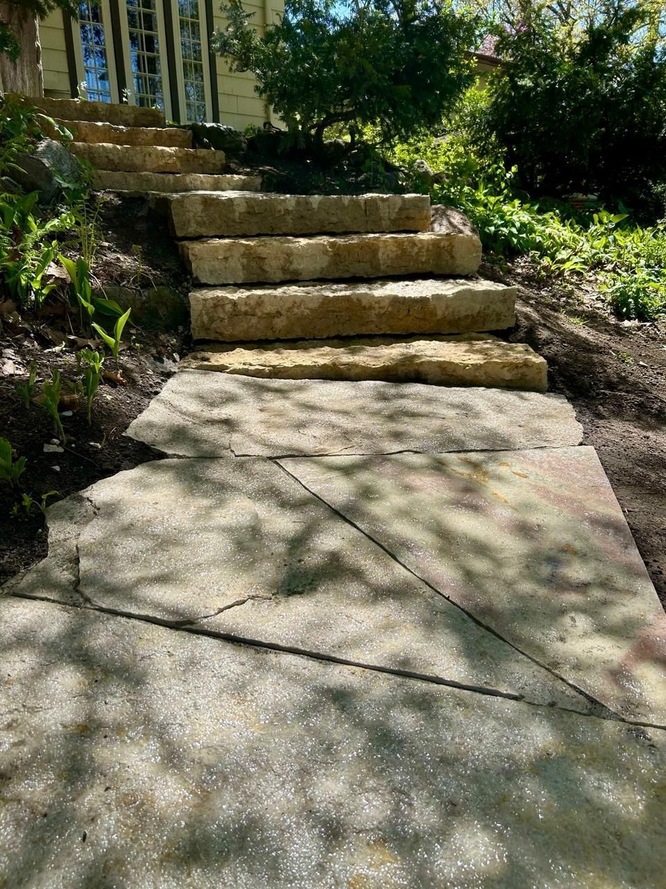 Back of a gray house with a patio and deck in a yard with brown leaves.