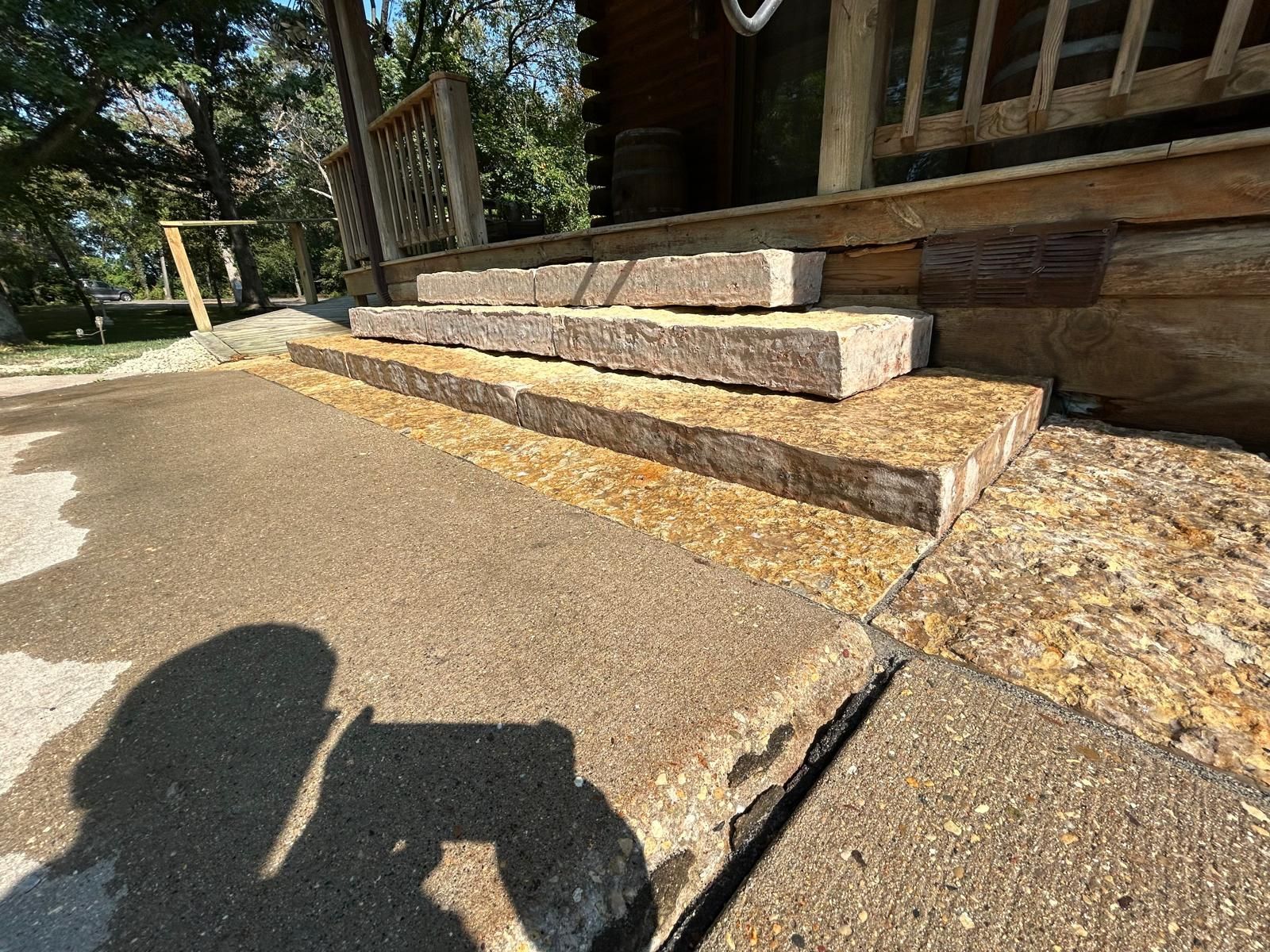 Stone steps leading to a wooden porch. Gravel in between the steps. Sunny day.