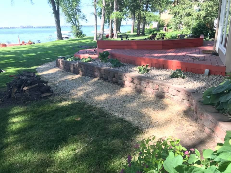 A patio with a fire pit and a view of a lake.