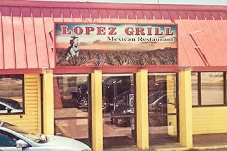 A white car is parked in front of a lopez grill mexican restaurant.