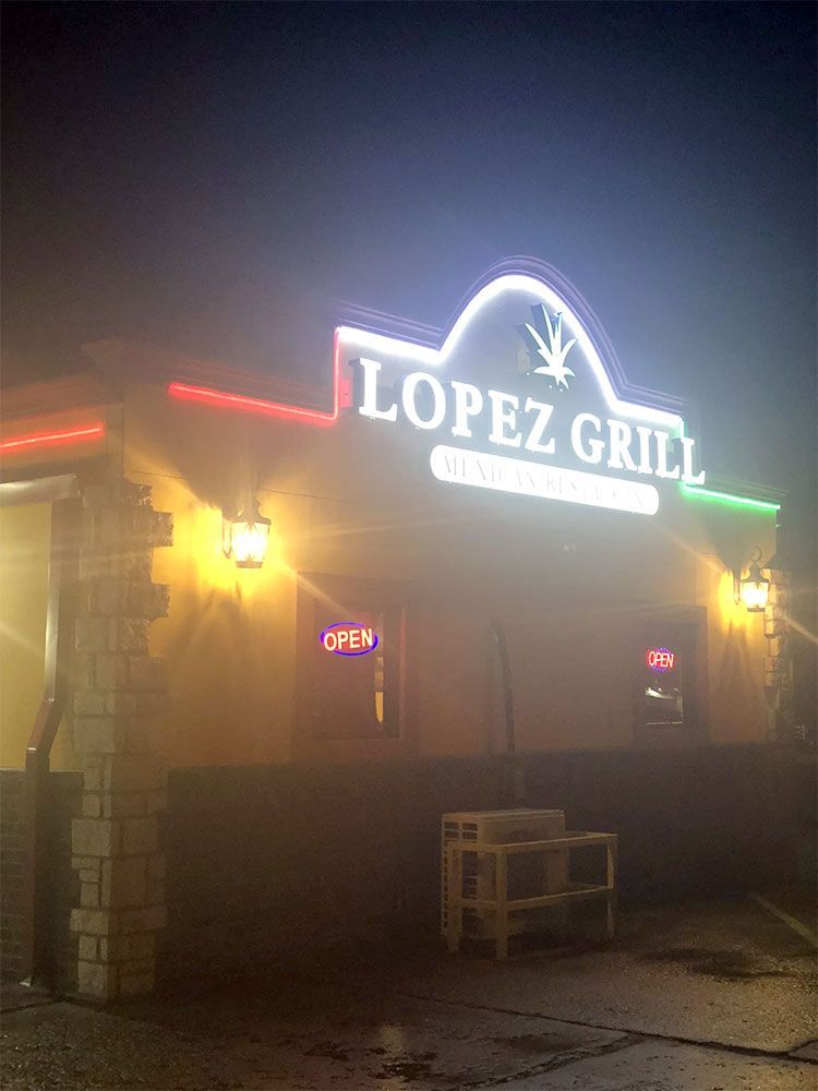 A restaurant called lopez grill is lit up at night.