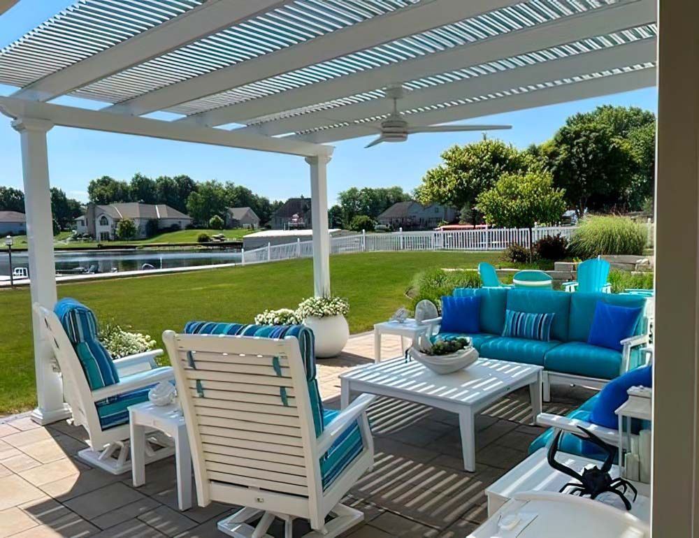 Patio with white pergola, turquoise seating, and lake view.