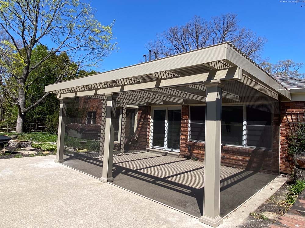 Beige patio cover with screen walls and a brick building, over a paved area.