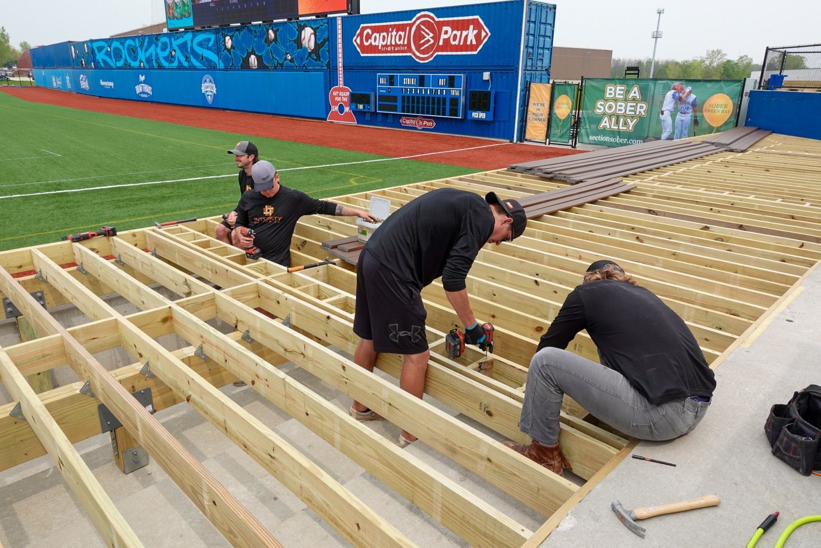 A group of people are working on a wooden deck.