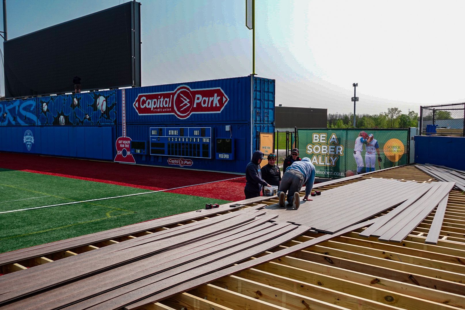 A group of people are working on a baseball field.