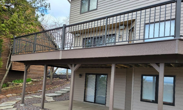 A large deck with a railing is sitting on the side of a house.