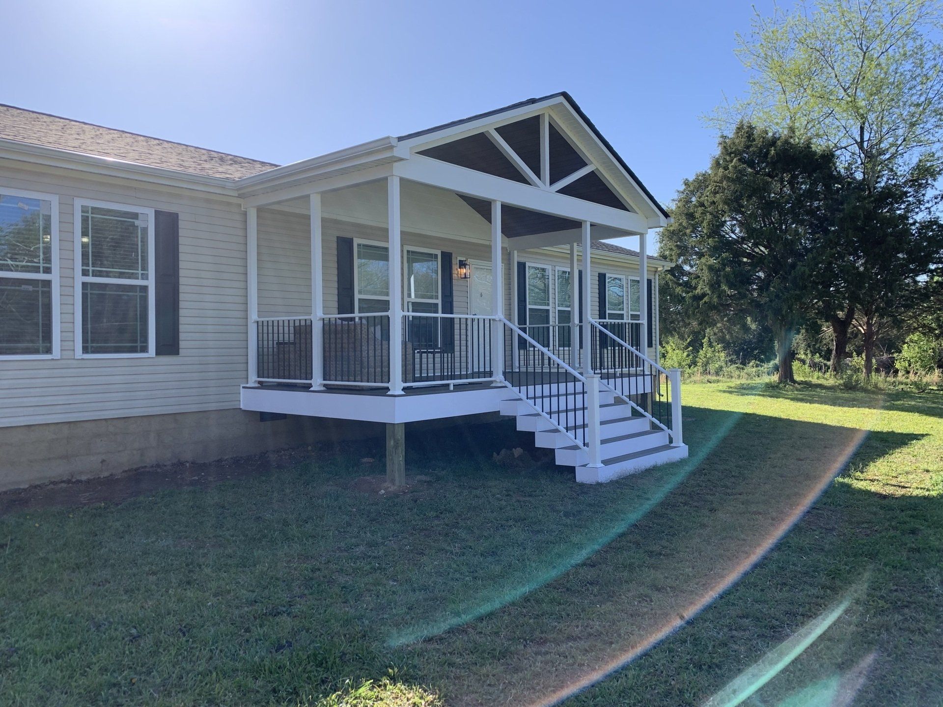 A white mobile home with a porch and stairs