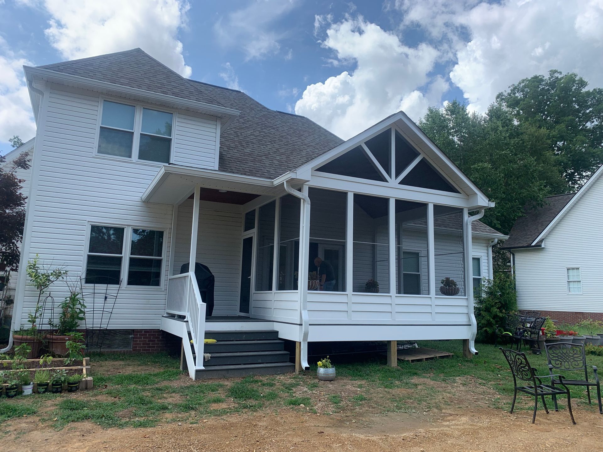 A white house with a screened in porch and stairs