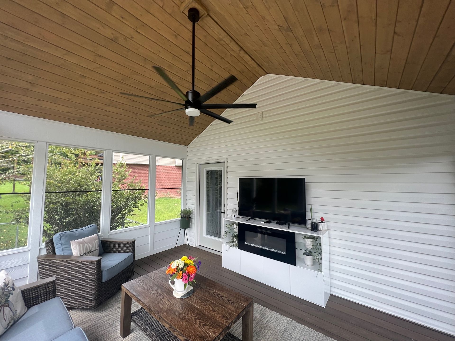 A living room with a ceiling fan and a flat screen tv.