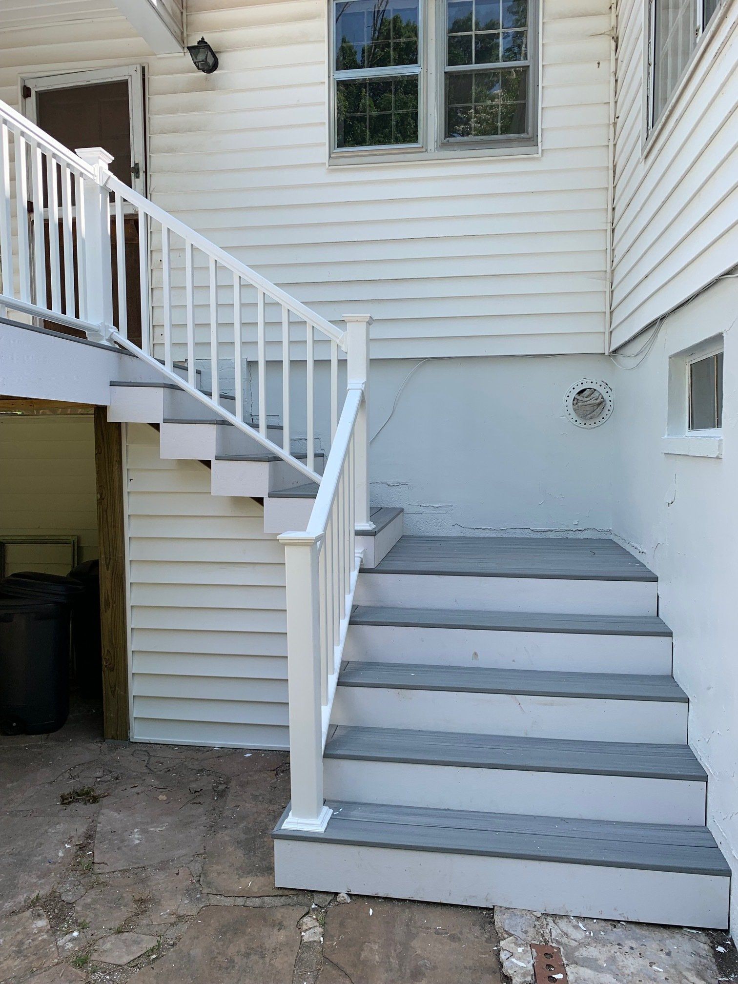 A white house with stairs leading up to it and a white railing.