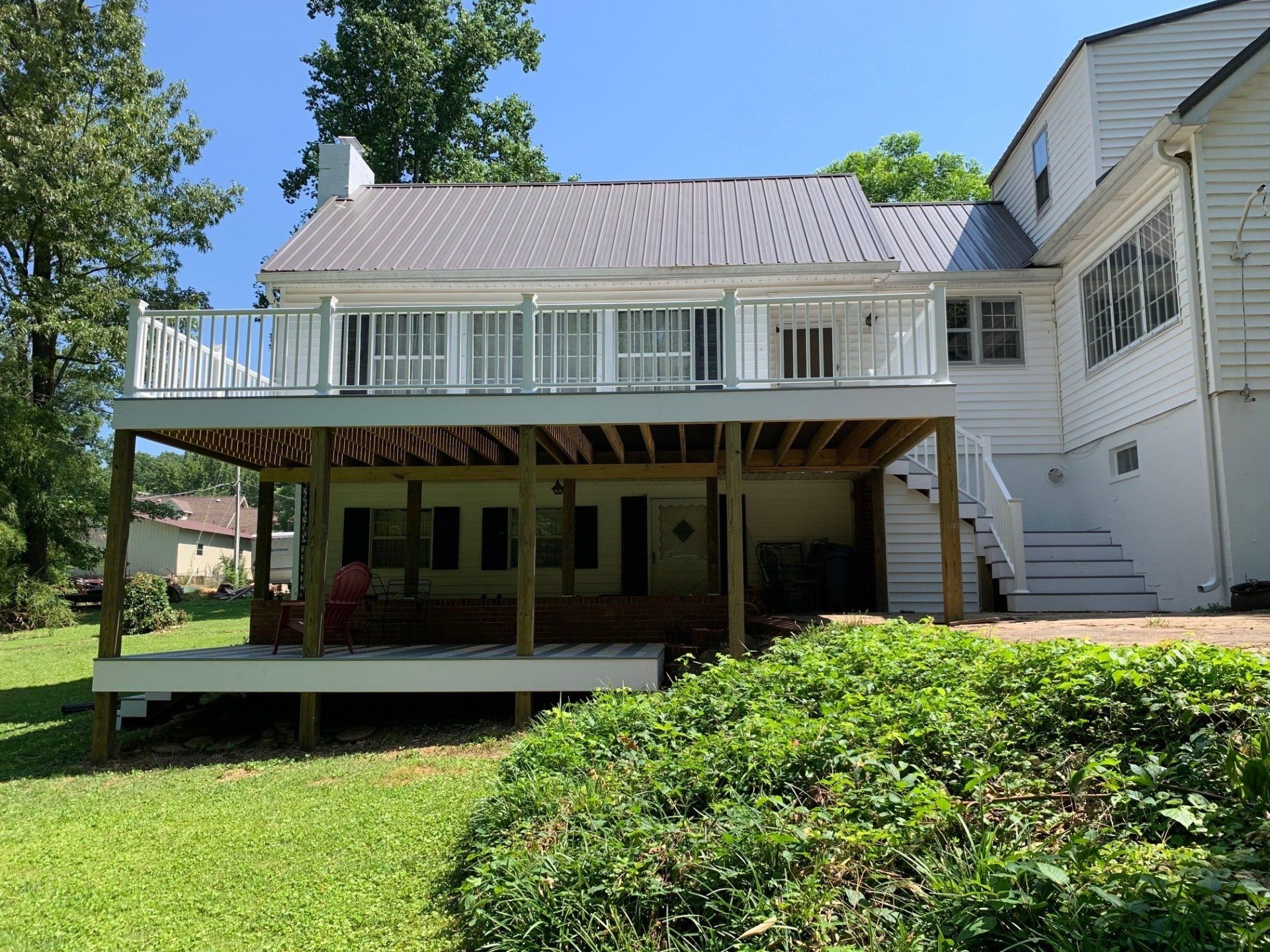 A large white house with a large deck in the backyard.