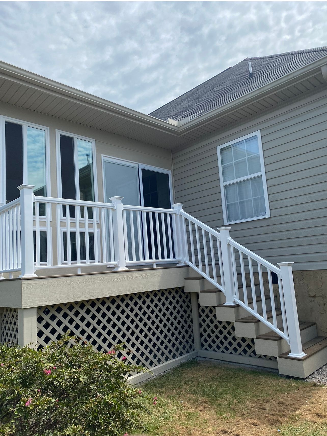 A house with a white deck and stairs leading up to it.
