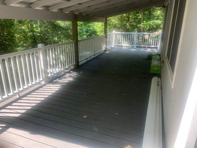 A large covered porch with a white railing and a window.