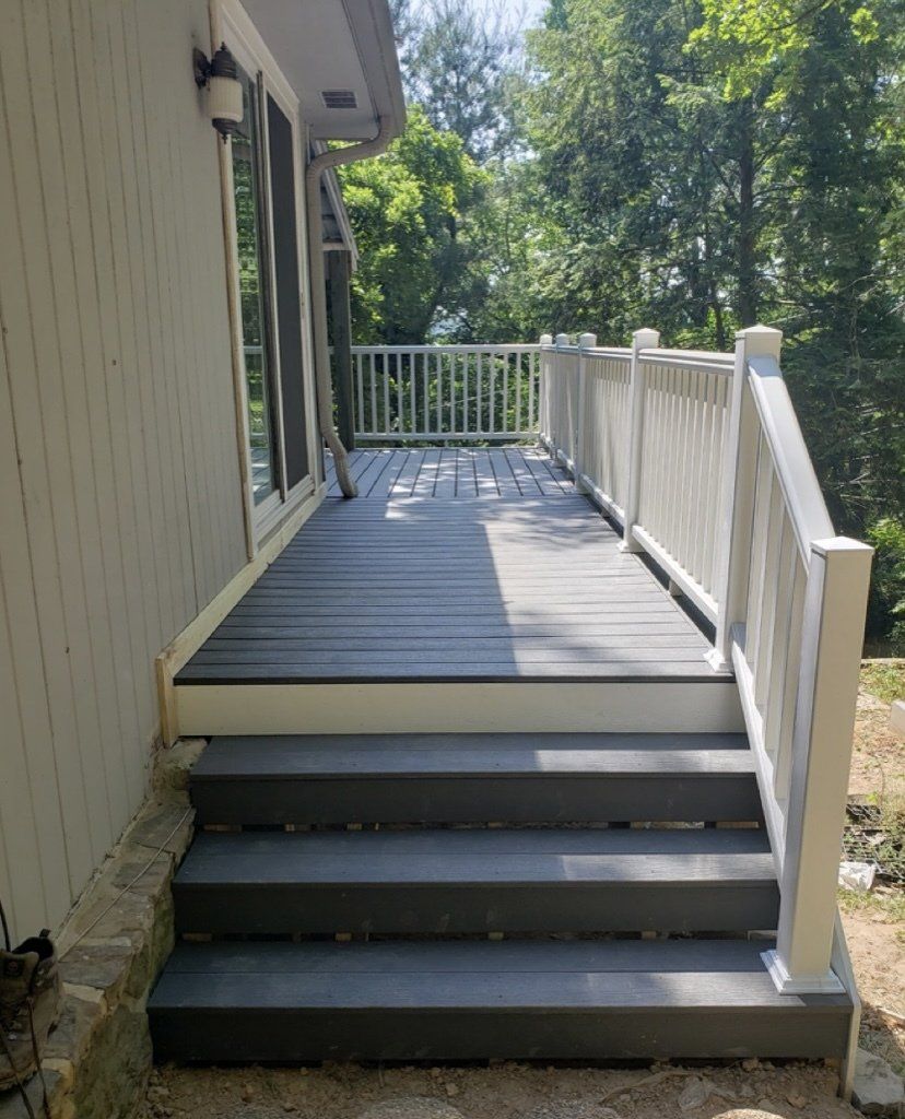 A deck with stairs and a white railing on the side of a house.