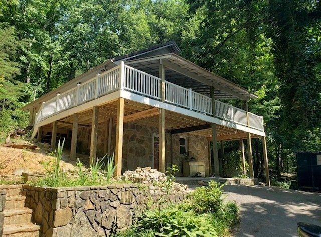 A house with a large deck in the middle of a forest.