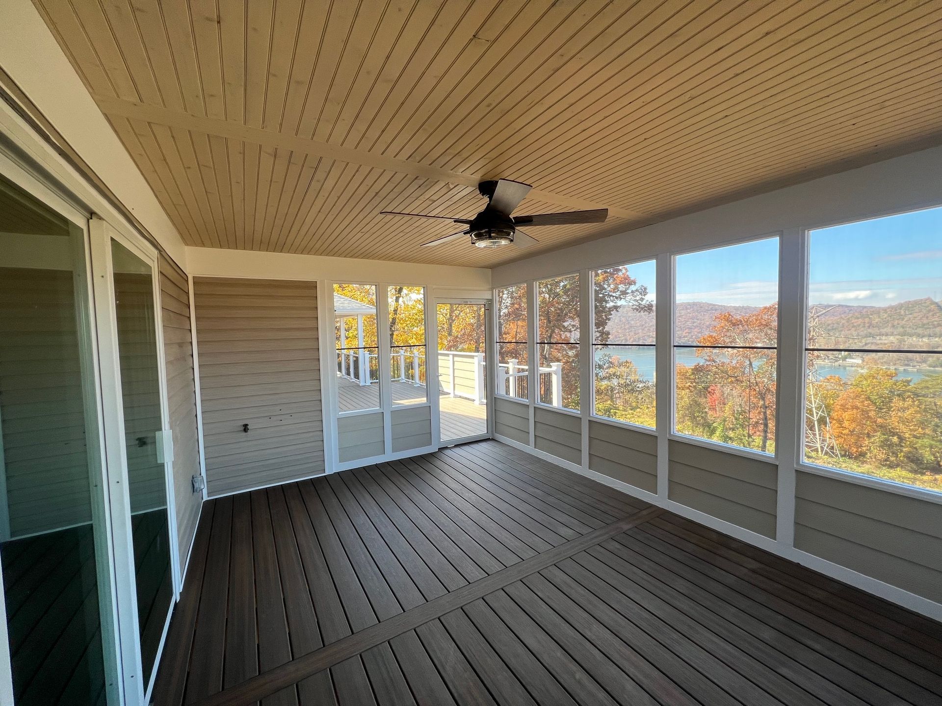 A screened porch with a ceiling fan