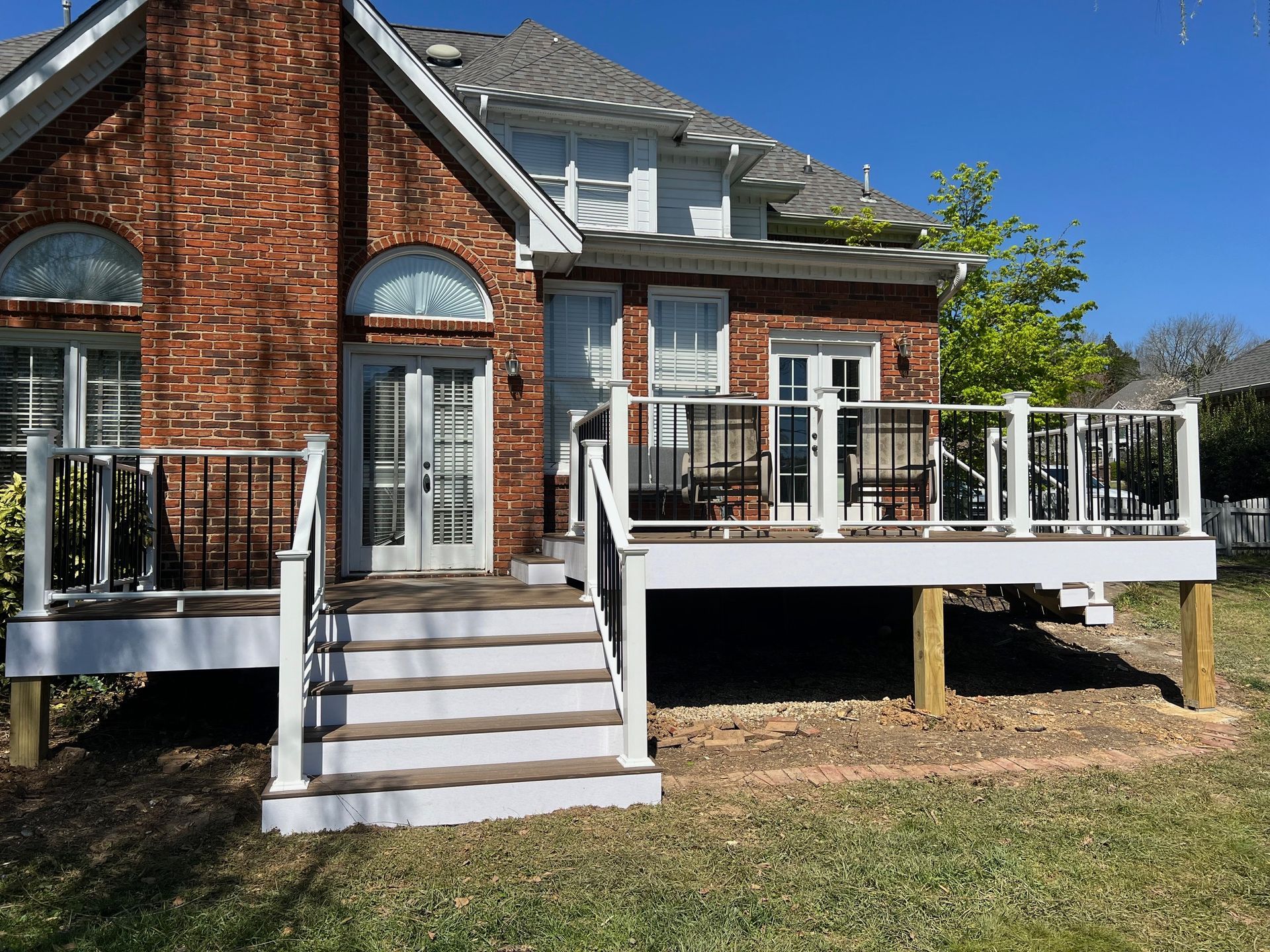 A brick house with a white deck and stairs in front of it.