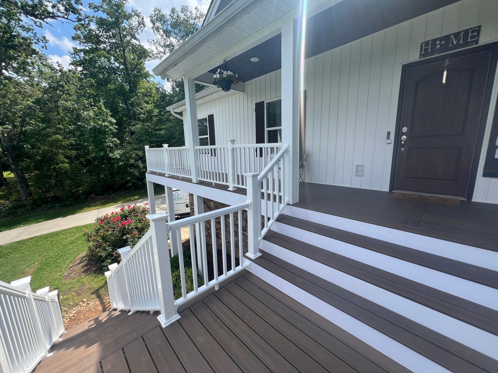 A white house with a large porch and stairs leading up to it.