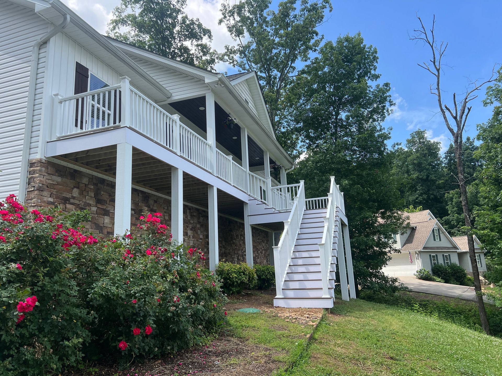 A large white house with a large deck and stairs.