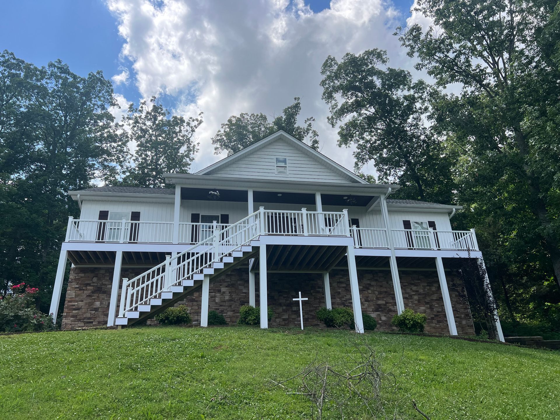 A large white house with a large deck and stairs