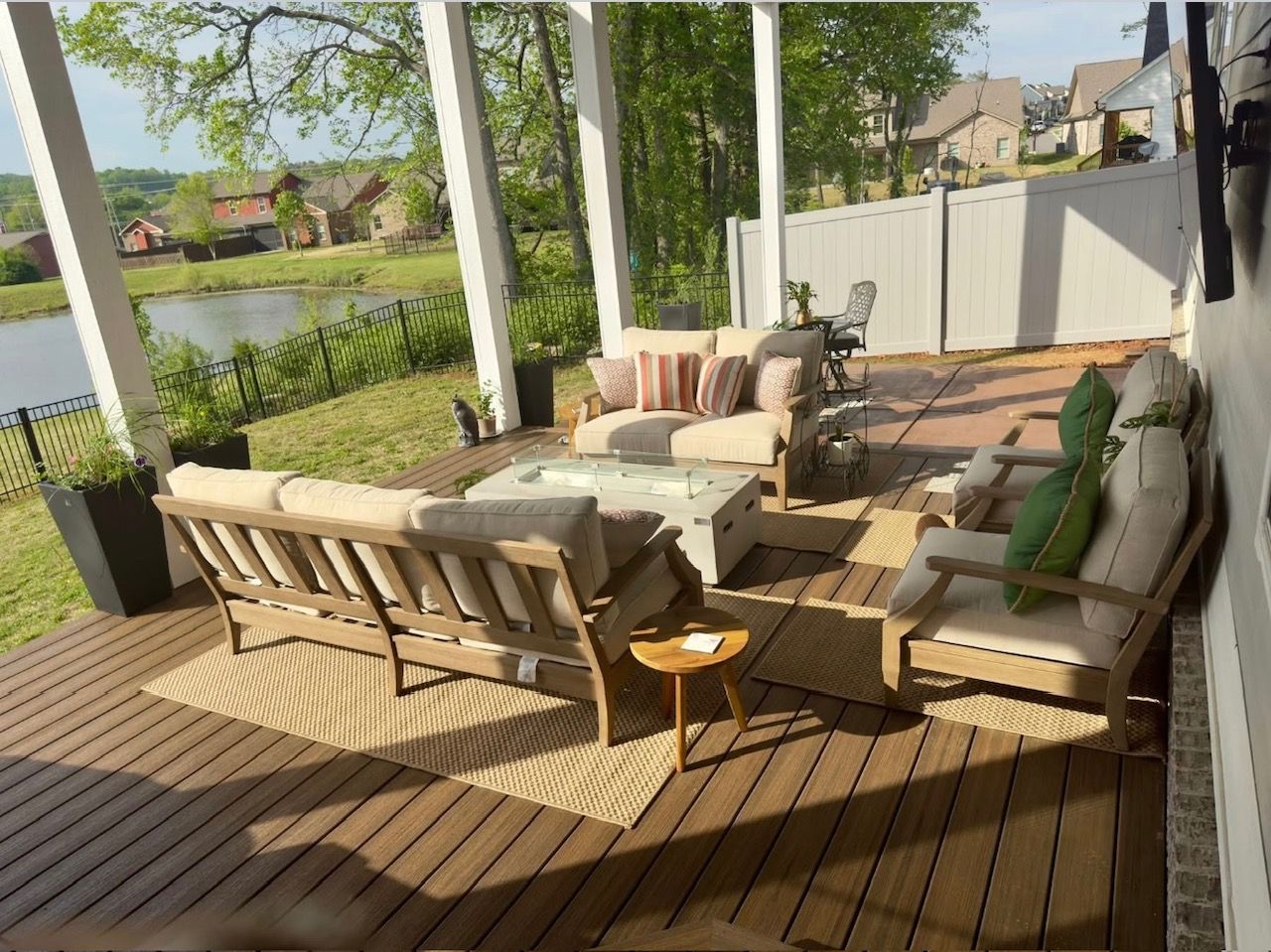 A deck with a lot of furniture on it and a view of a lake.