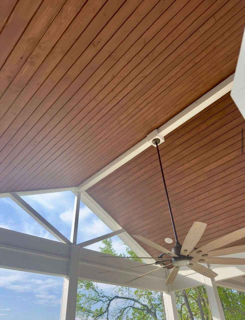 A wooden ceiling with a ceiling fan hanging from it