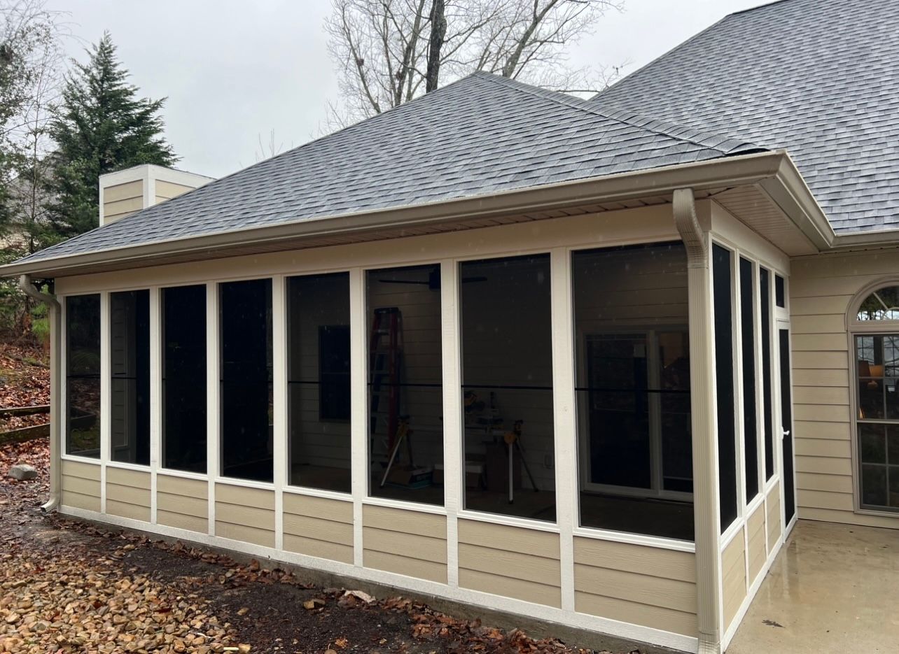 A screened in porch on the side of a house.
