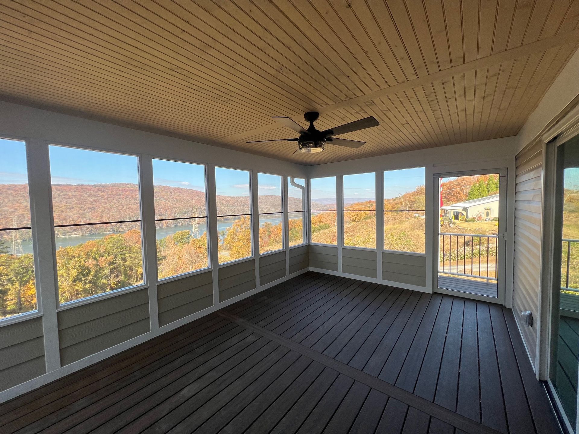 A screened porch with a ceiling fan