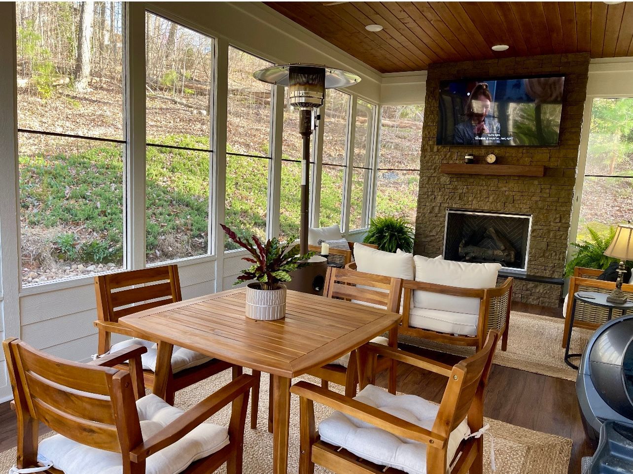 A screened in porch with a table and chairs and a fireplace.