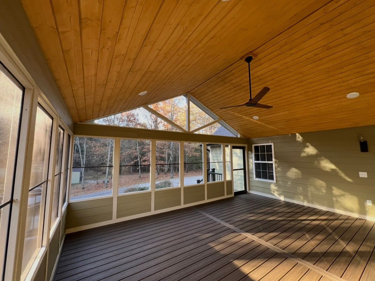 Screened-in porch with wood ceiling and floor, glass windows, and a ceiling fan.