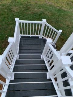 A set of stairs leading up to a deck with a white railing.
