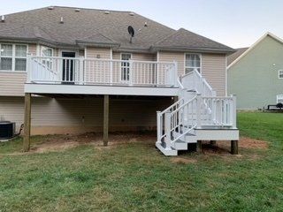 A white deck with stairs is in the backyard of a house.