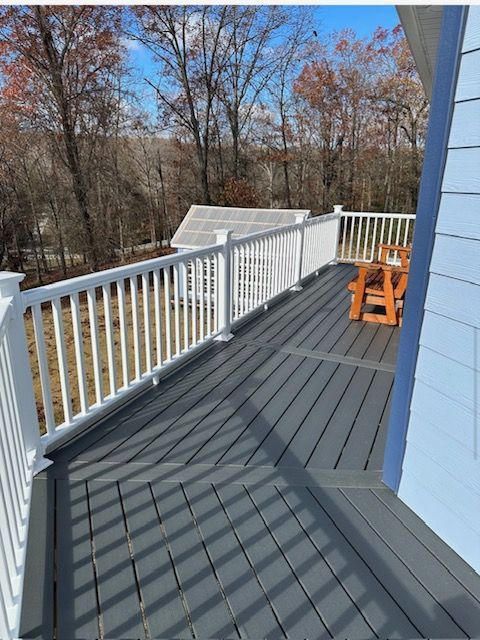 A deck with a white railing and a chair on it