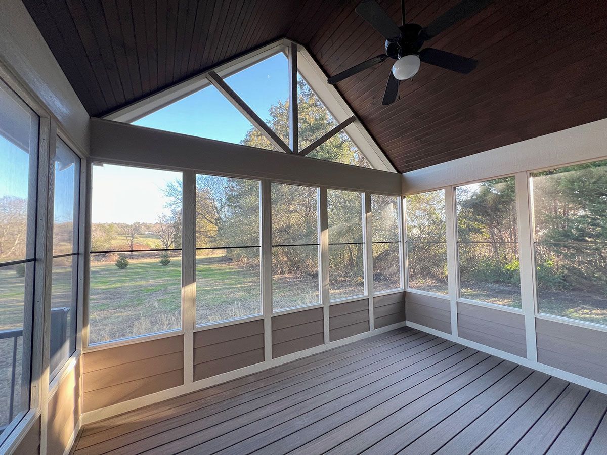 A screened in porch with a ceiling fan and a lot of windows