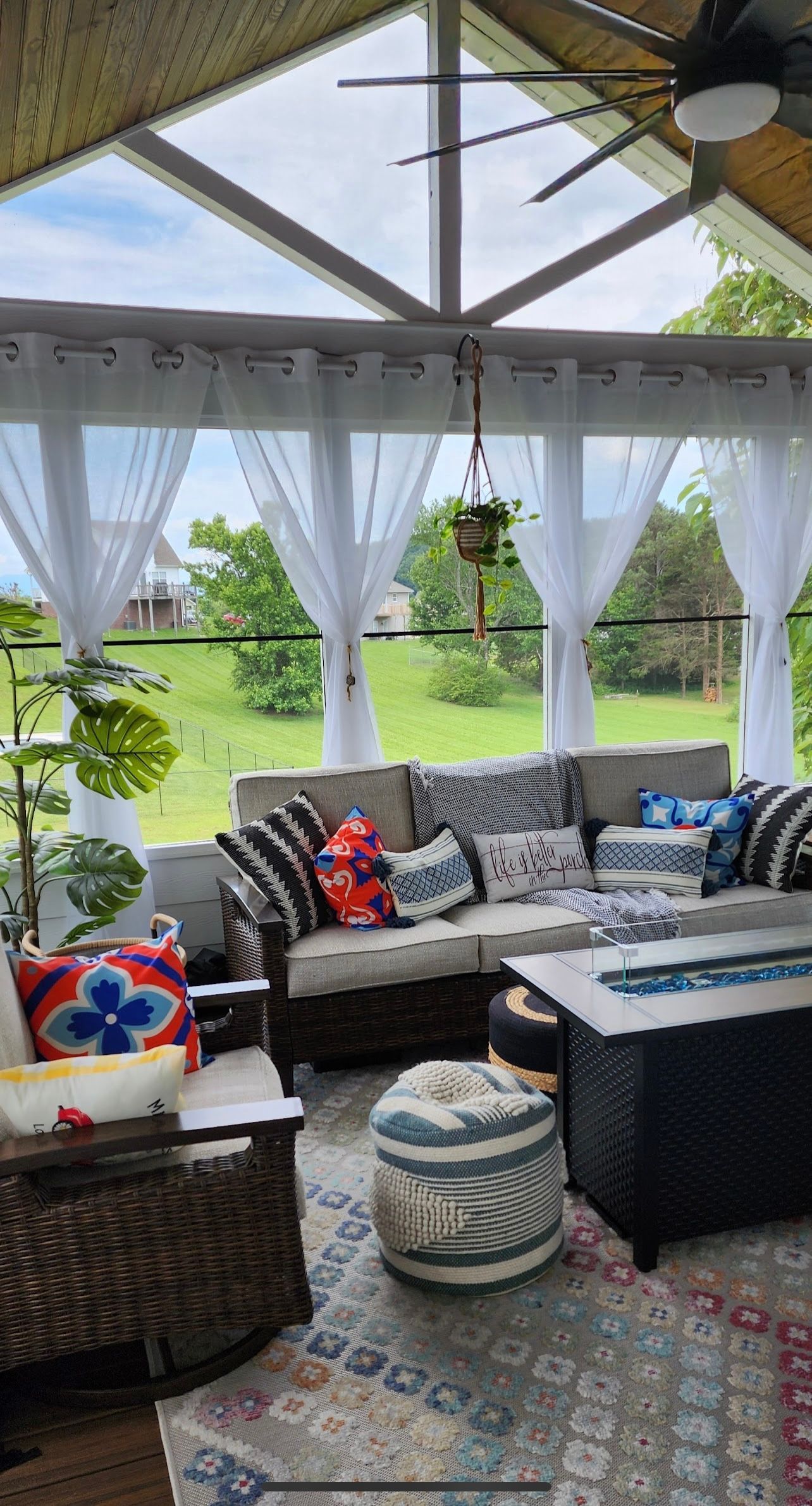A screened in porch with furniture and a ceiling fan.