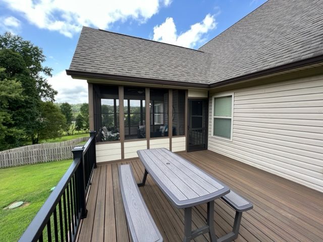 A screened in porch with a picnic table and benches