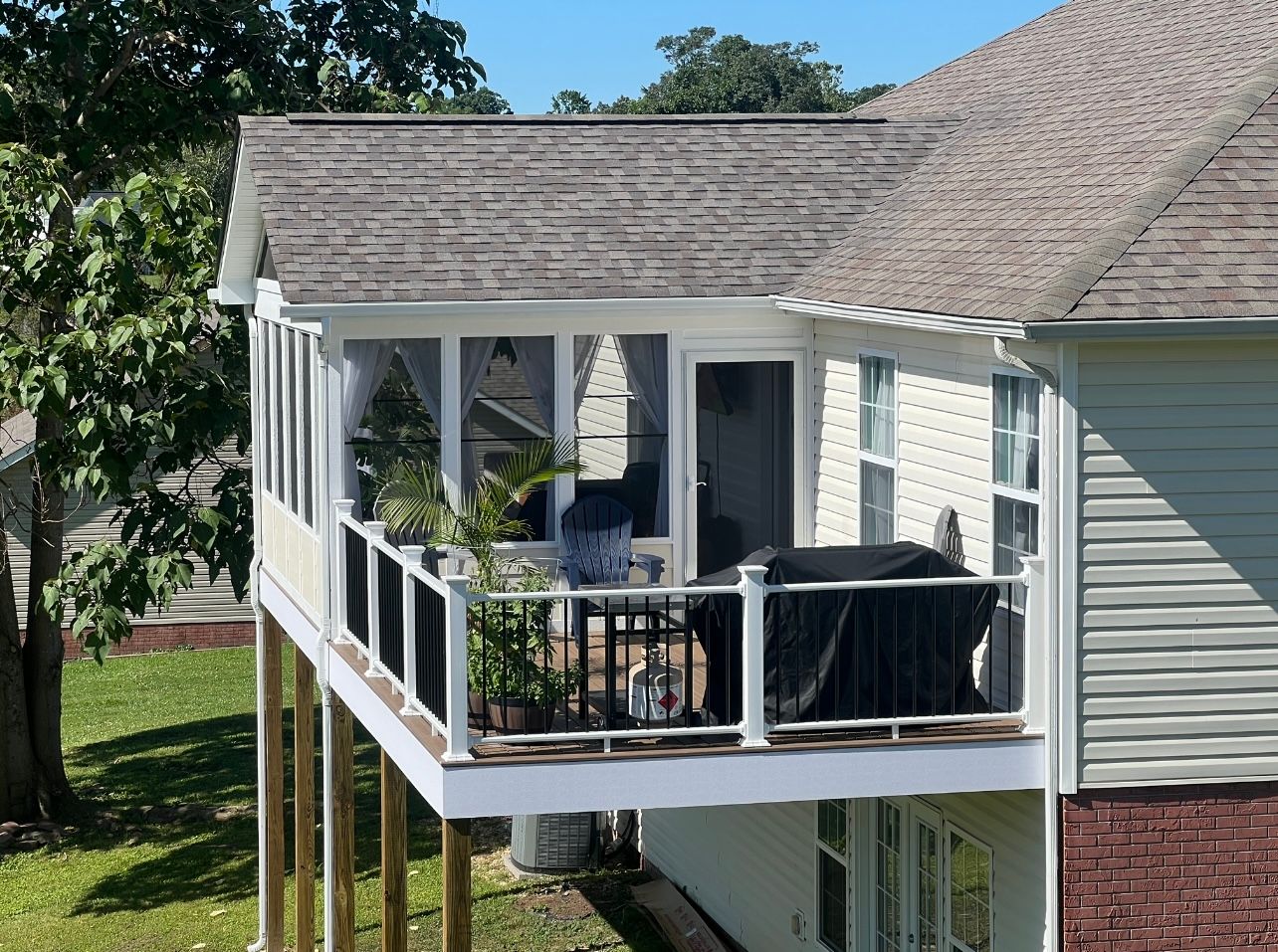 A house with a screened in porch and a grill on it.