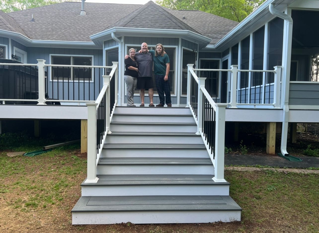 A group of people are standing on a deck in front of a house.