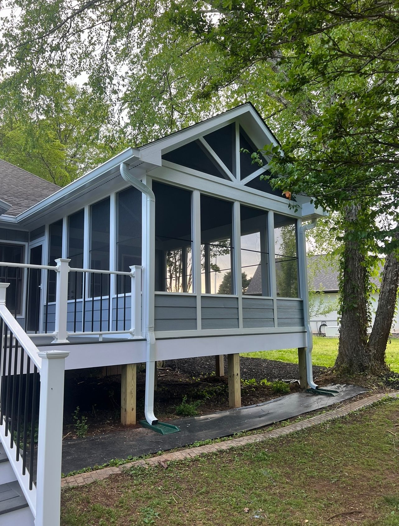 A screened in porch with a white deck and stairs in front of a house.