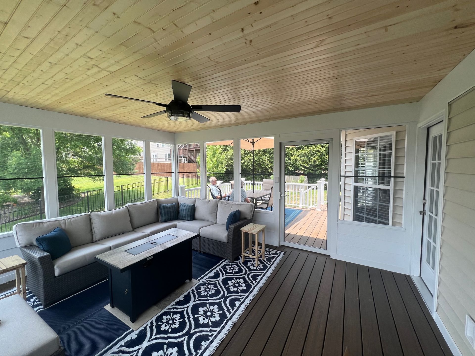 A screened in porch with a couch , coffee table , and ceiling fan.