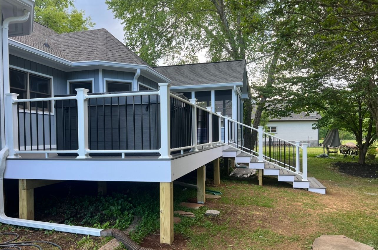 A large deck with stairs leading up to it is in the backyard of a house.