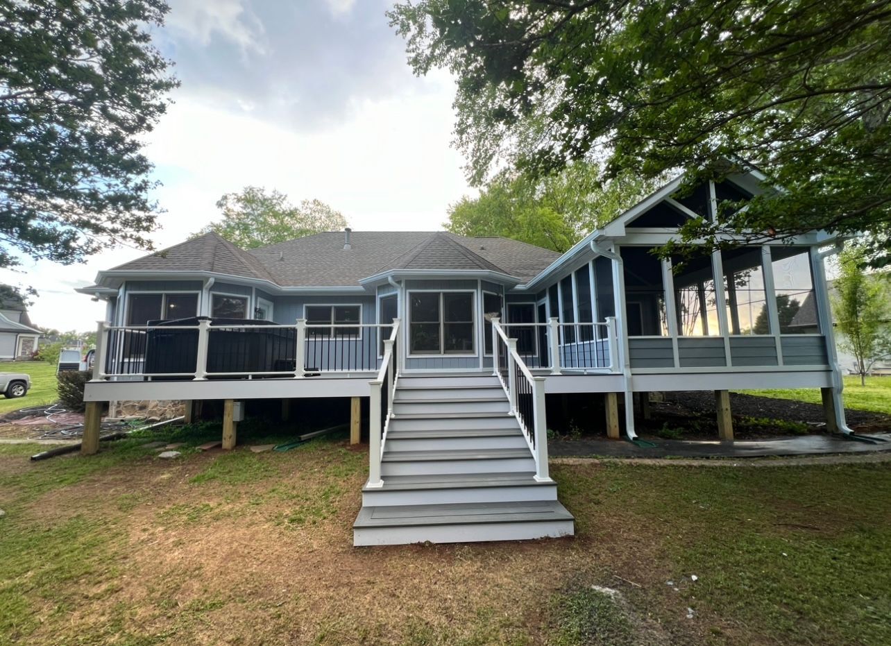 The back of a house with a screened in porch and stairs.