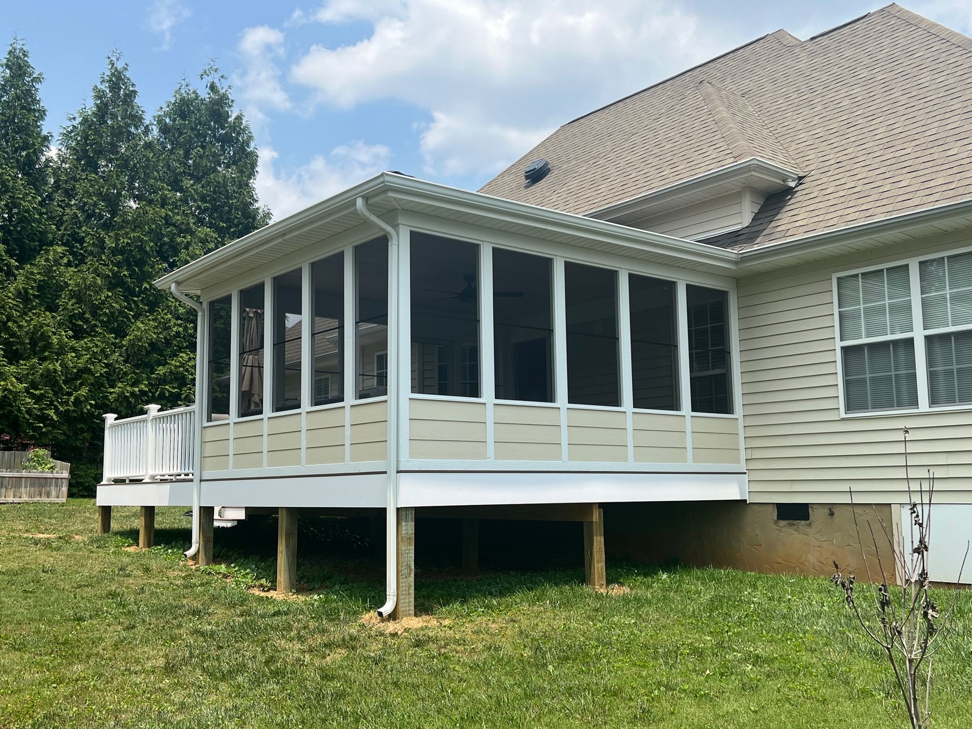 A screened in porch on the side of a house.