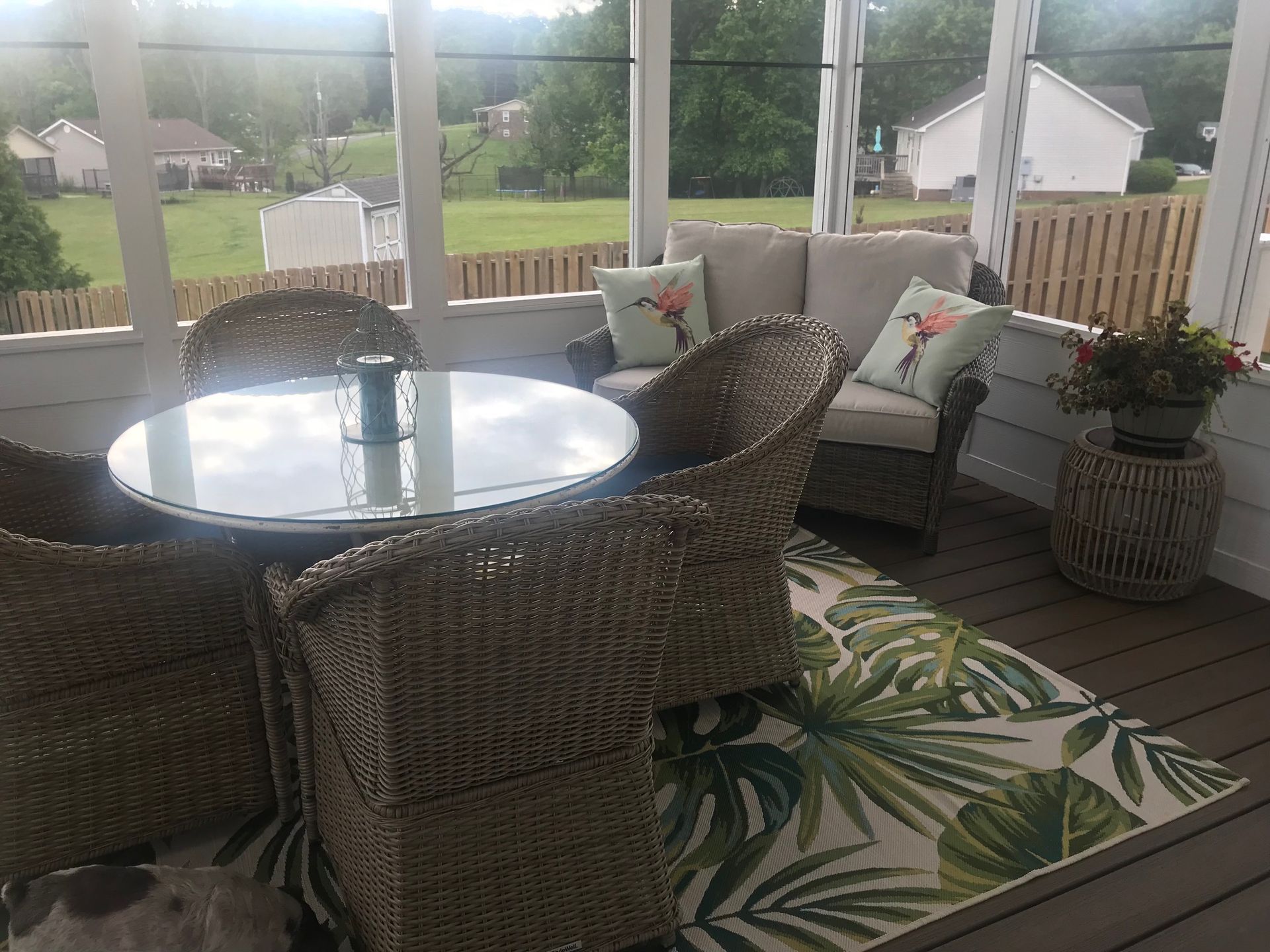 A screened in porch with wicker furniture and a rug.