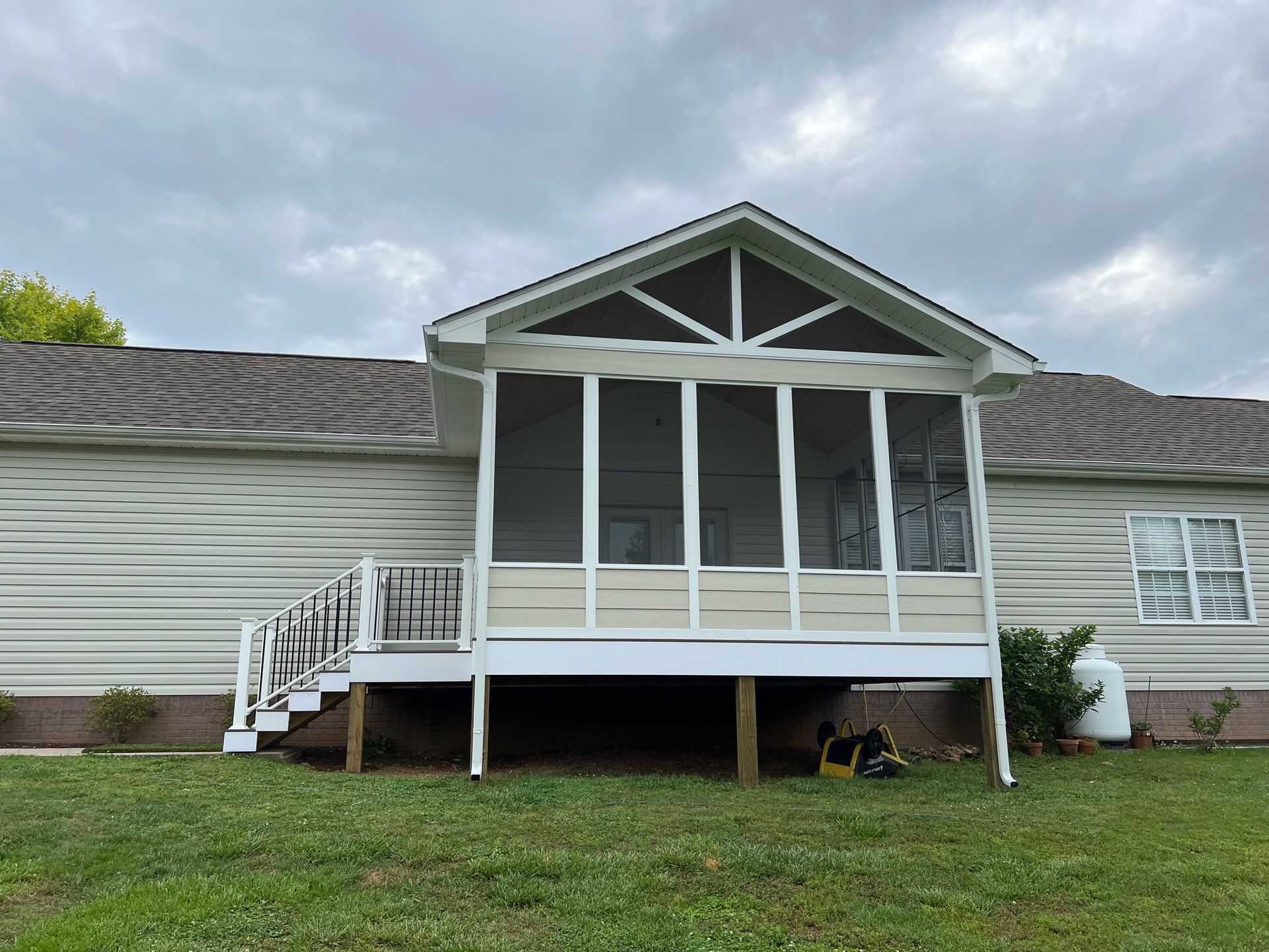 A white house with a screened in porch and stairs.