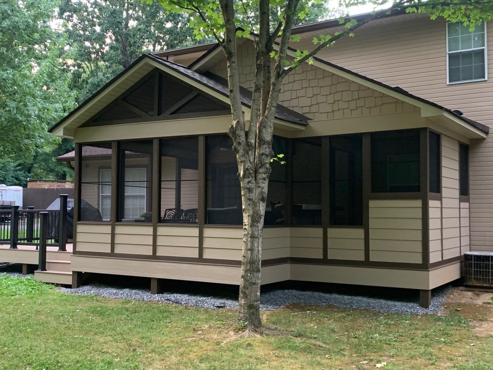 A house with a screened in porch and a deck.