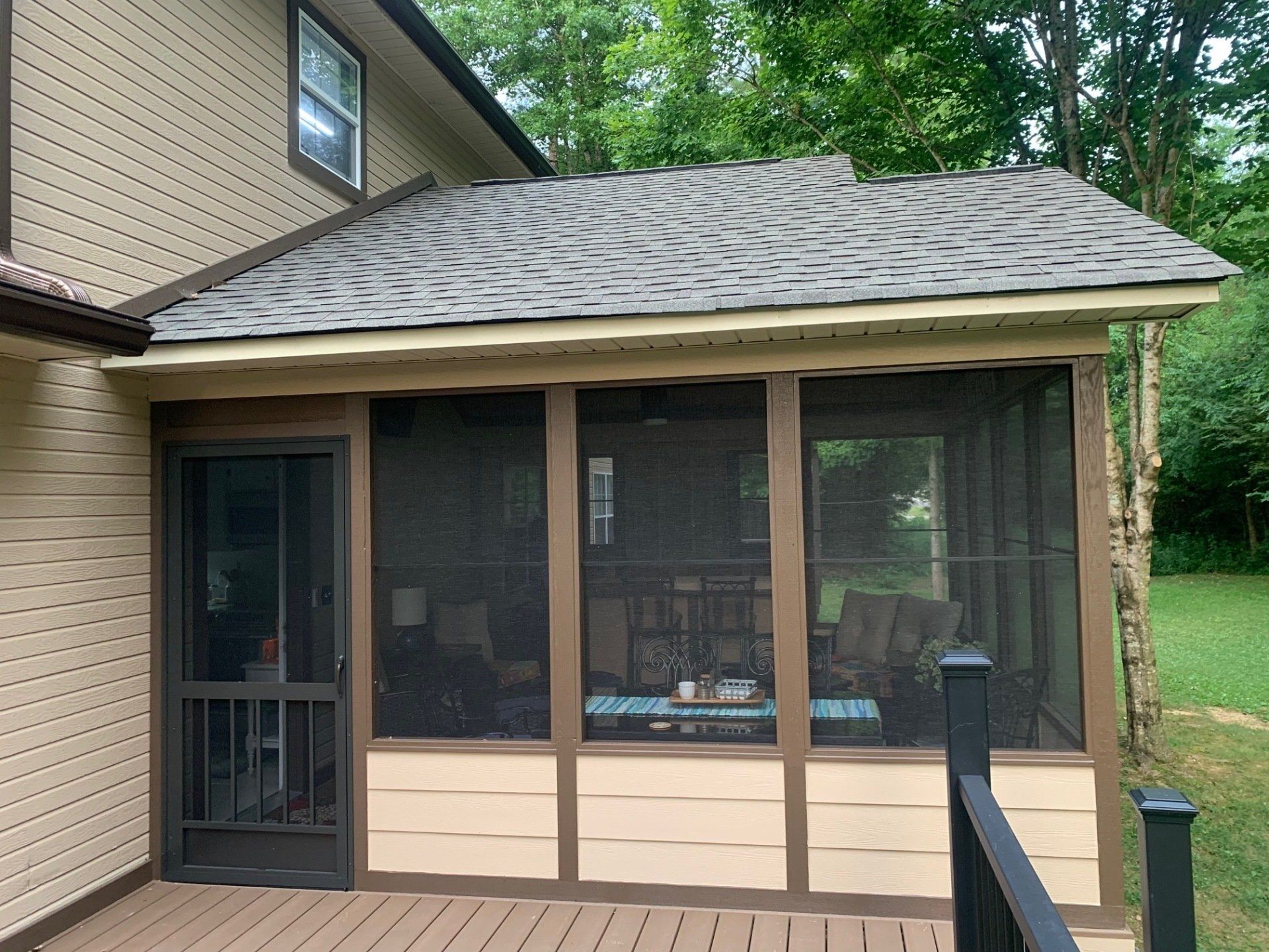 A screened in porch on the side of a house.