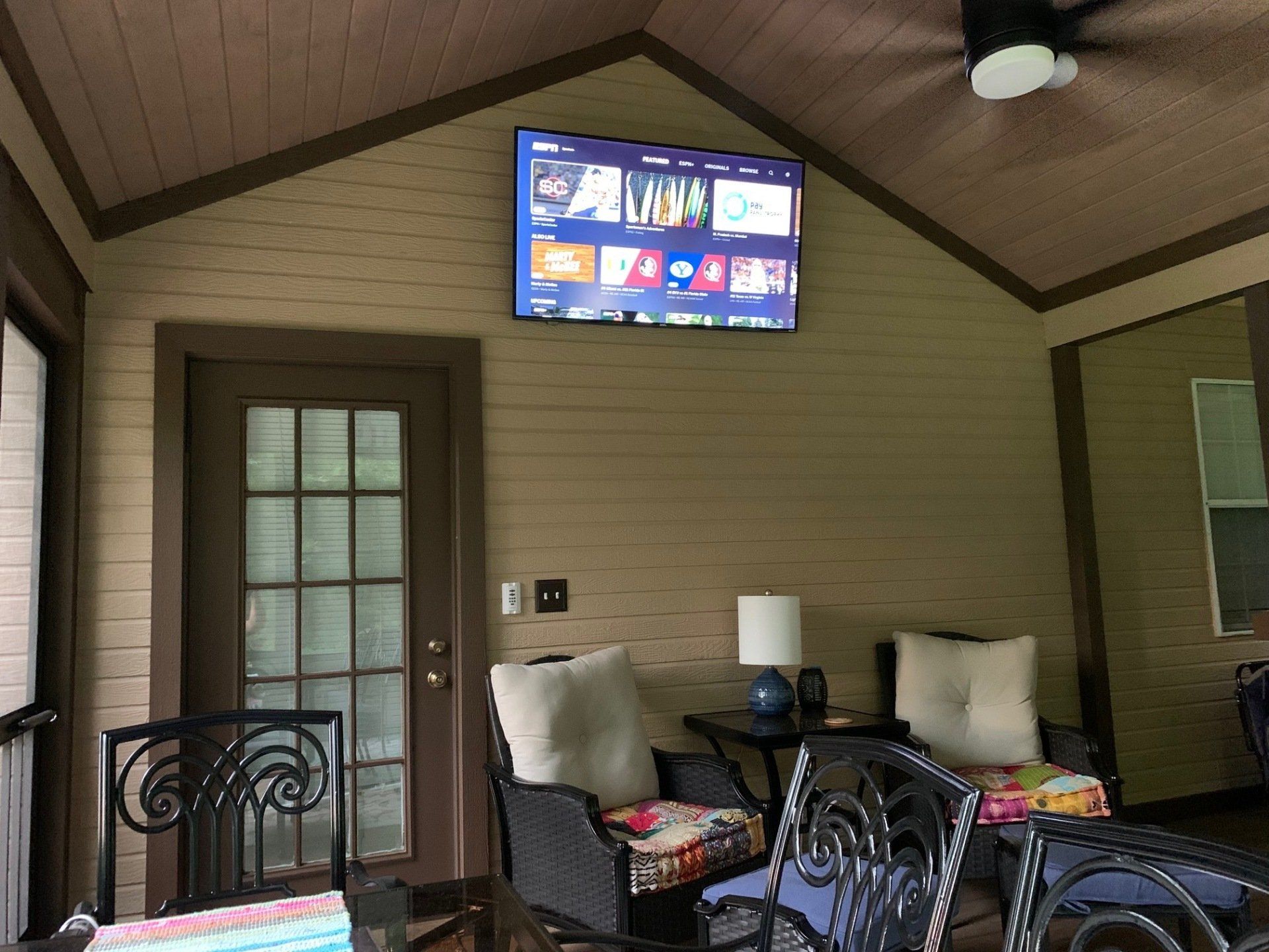 A living room with a flat screen tv hanging from the ceiling.