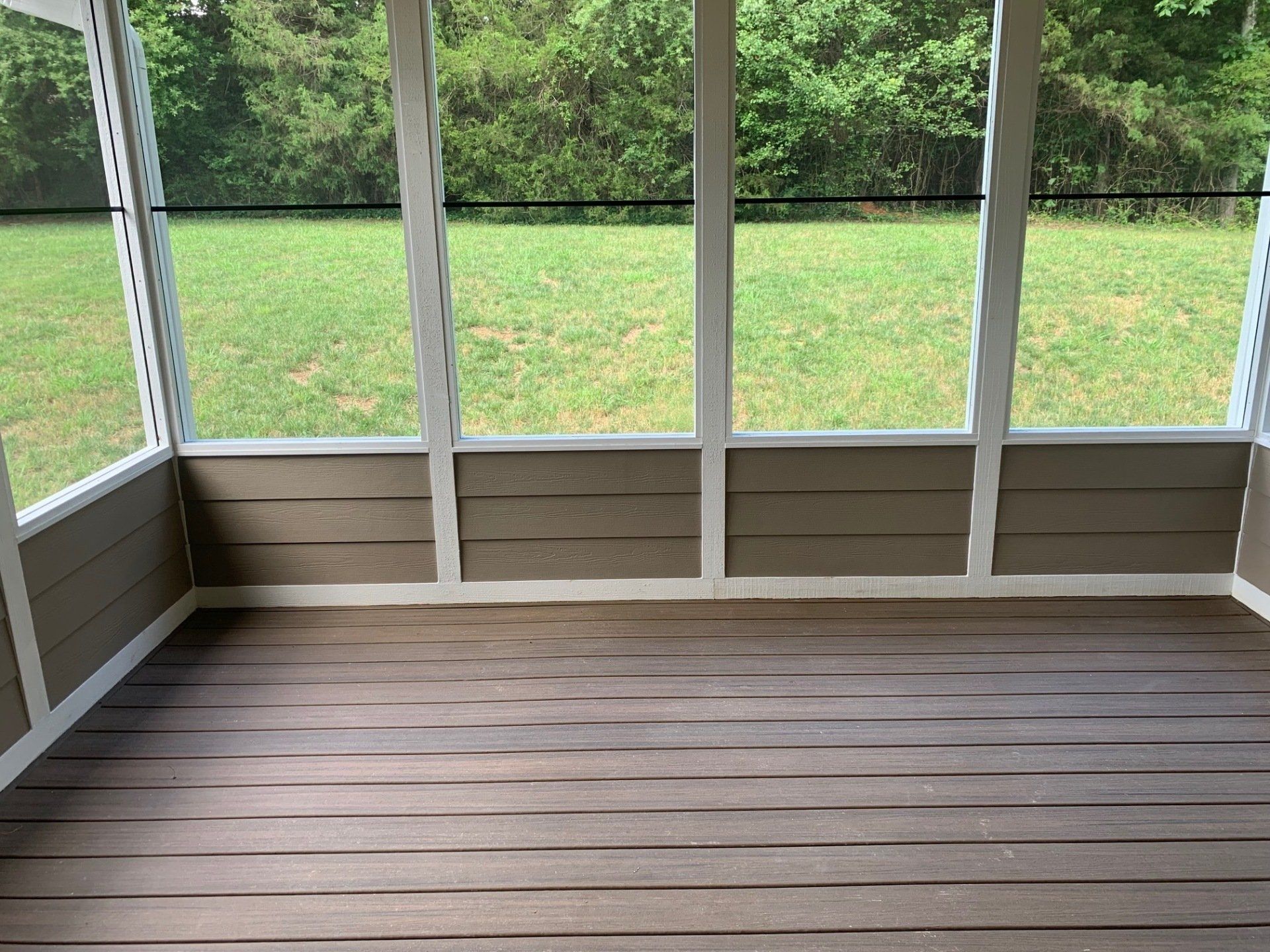 A screened in porch with a lot of windows and a wooden floor.